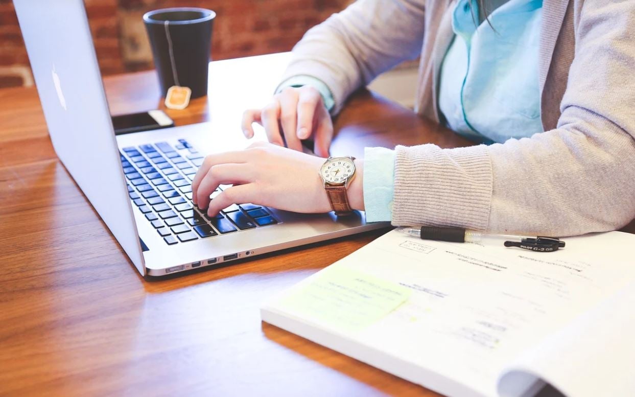 Person working on a laptop with a cup of tea